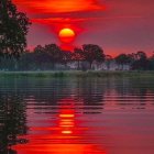 Vibrant red and purple sunset over calm river and cottages