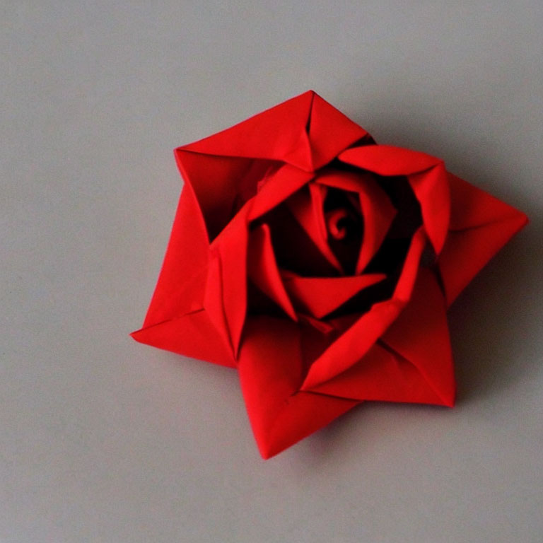 Vibrant red origami rose on light grey background