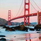 Golden Gate Bridge at Sunset with Serene Waters and Rocks