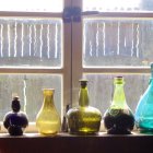 Vibrant glass bottles on sunlit windowsill with refracted light and bubbles.