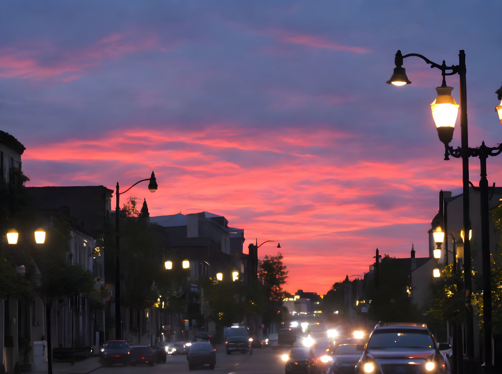 Vibrant sunset over urban street with pink and blue hues