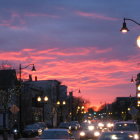 Urban street scene: dusk with streetlights, car headlights, pink and purple sunset sky