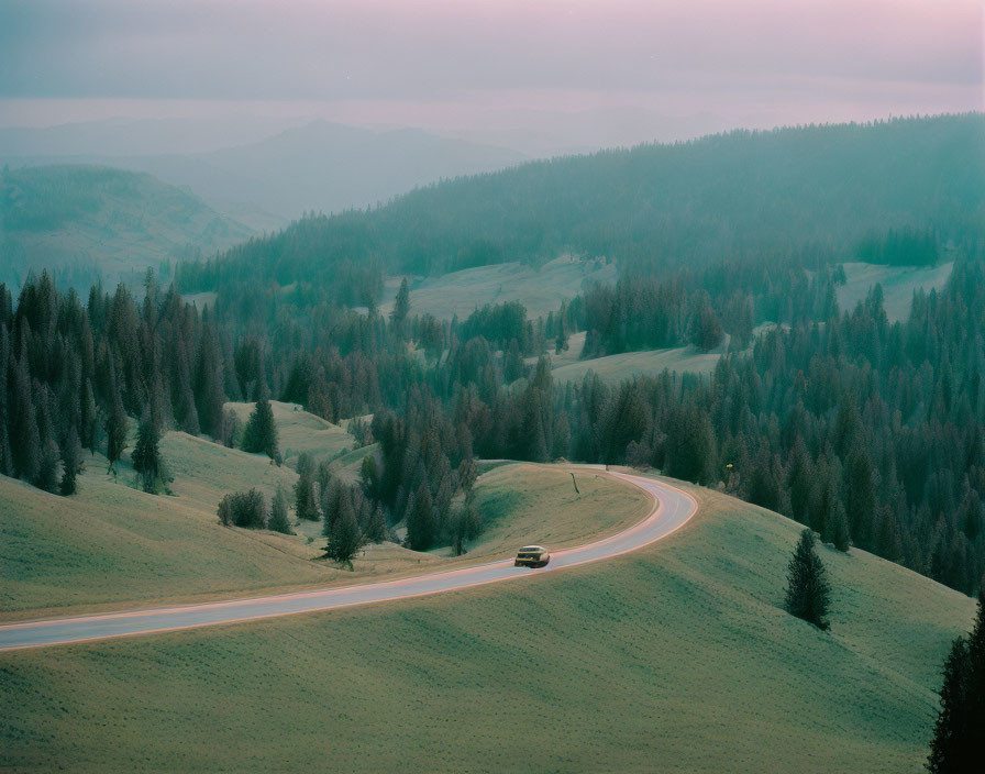 Tranquil hilly landscape with winding road and car