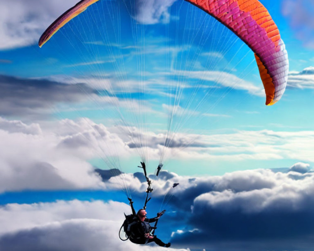 Paraglider flying over lush mountains with orange wing in blue sky
