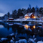 Snow-covered house and trees by calm lake in serene winter scene