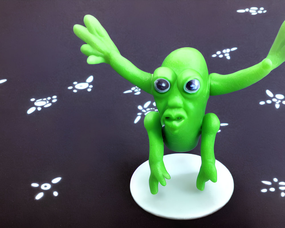 Green Alien Figurine with Large Eyes and Outstretched Arms on White Stand against Black Background
