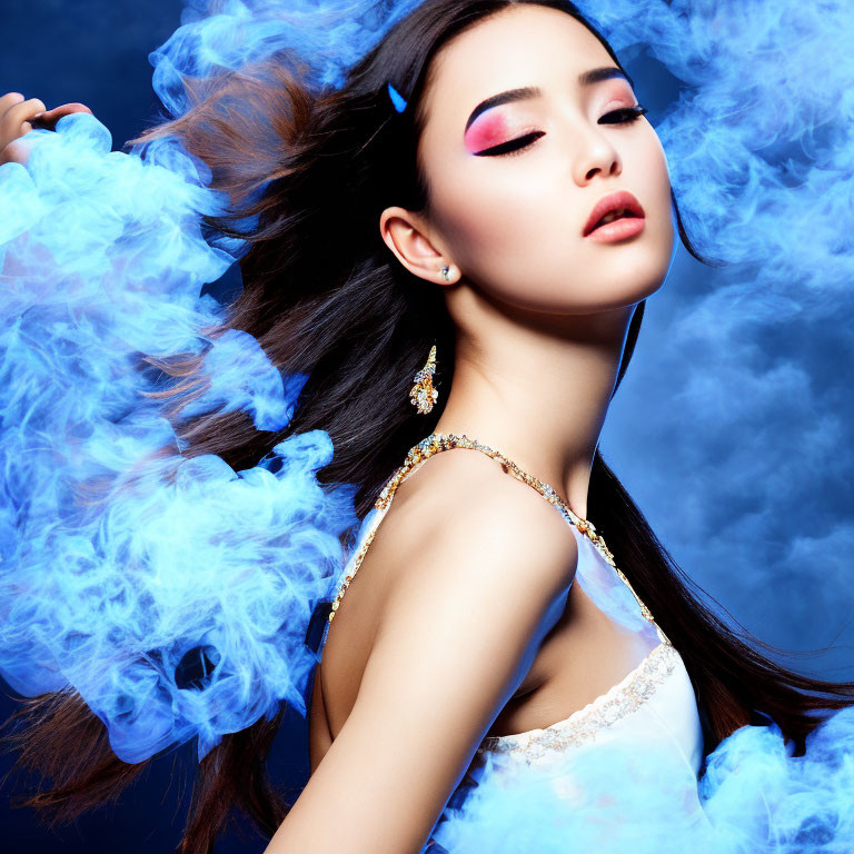 Woman with flowing hair and makeup in white dress surrounded by blue smoke on dark blue background