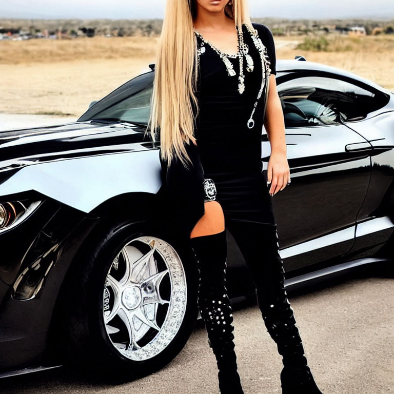 Woman in black dress and high-heeled boots posing next to sleek black sports car.