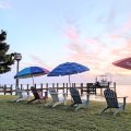 Tranquil Sunset Beach Scene with Lounge Chairs, Parasols, and Boats