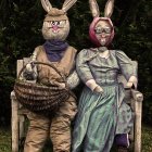 Anthropomorphic rabbit couple with grey owls, jewelry, and mystical orb on floral backdrop