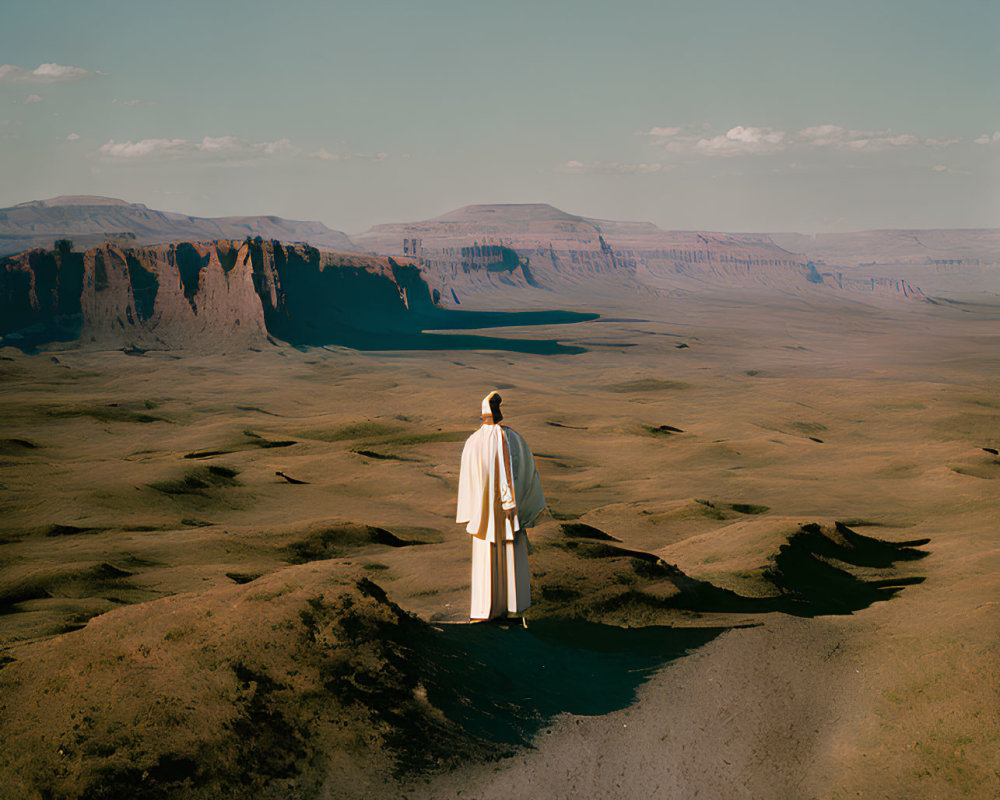 Solitary figure in vast desert landscape with towering cliffs
