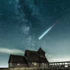 Rustic wooden barn under starry night sky with dramatic cloudscape