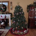 Festive Christmas scene with decorated tree, elves, fireplace, and window