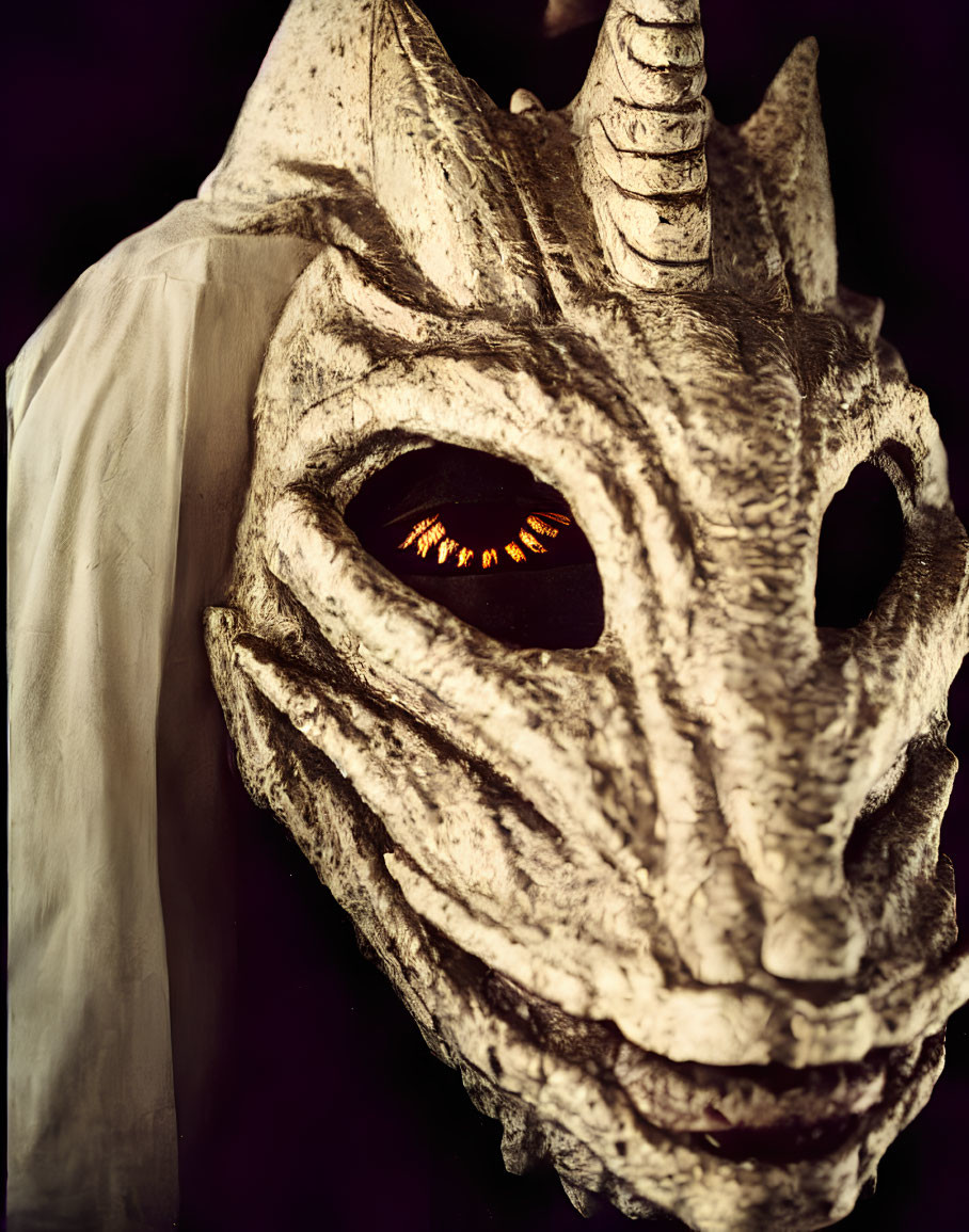 Detailed Dragon Mask with Orange Eyes and Horn, White Cloak on Dark Background