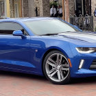 Blue Modern Muscle Car with Black Stripes and Chrome Wheels Parked in Front of Building