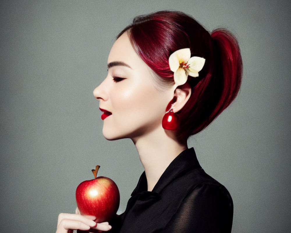 Red-haired woman in ponytail with apple, black outfit, red earrings, and white flower.