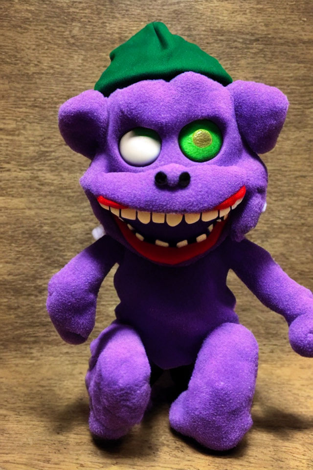Purple Creature Plush Toy with Exaggerated Smile and Green Hat on Wooden Background
