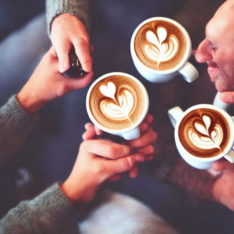 Three People Holding Latte Art Mugs Closely