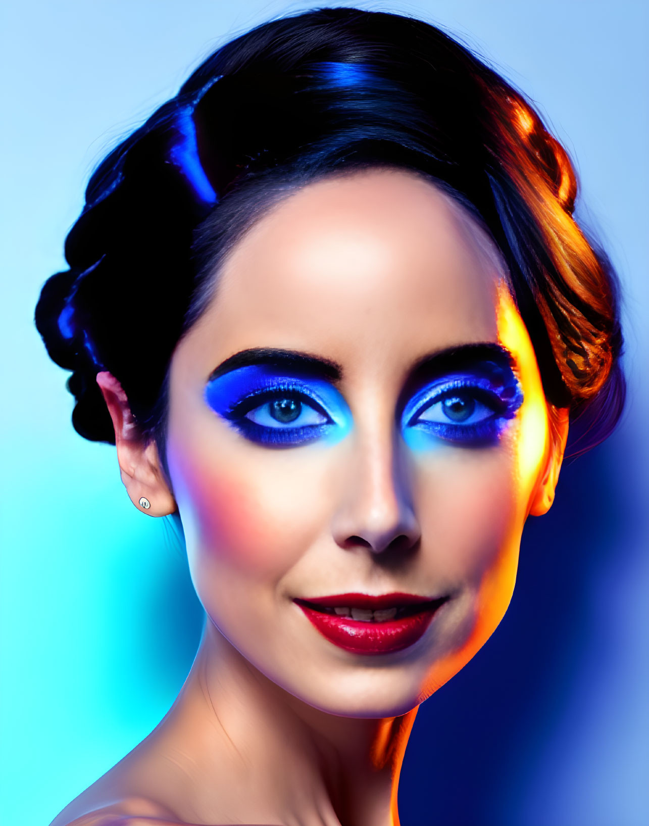 Striking blue eye makeup and red lips on woman against gradient background