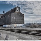 Industrial landscape with grain elevators and train tracks under clear blue sky