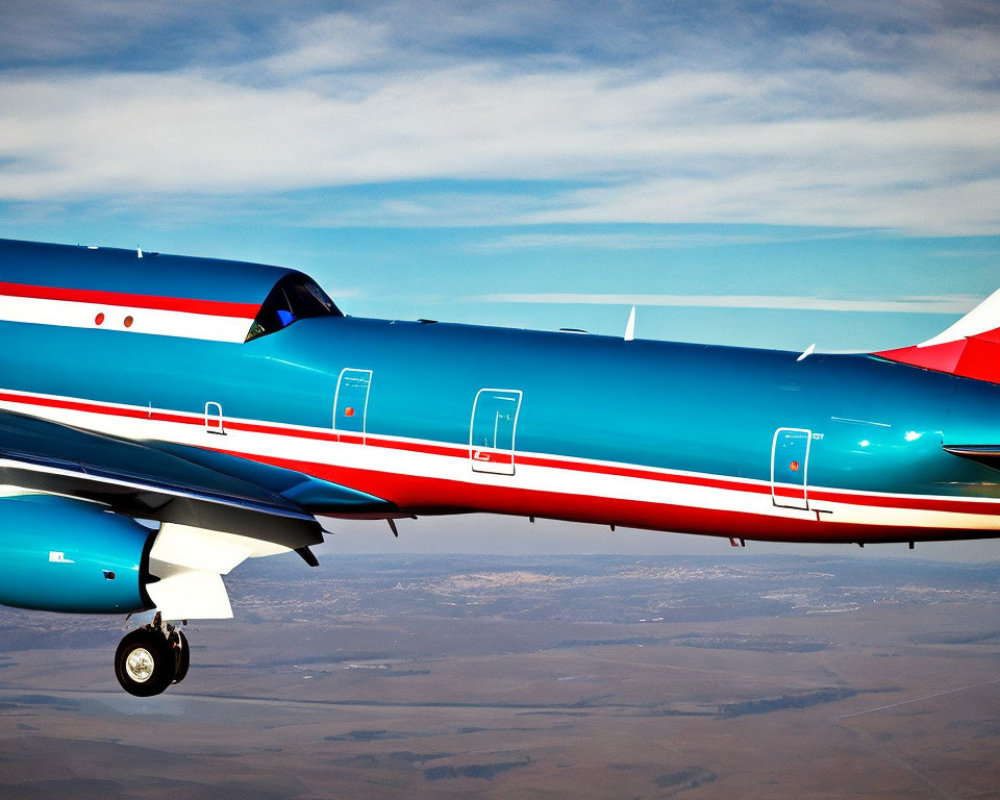 Vibrant blue and red jet soaring in blue skies over distant brown landscape