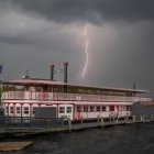Vintage paddle steamer at wooden pier under dramatic twilight sky