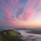 Tranquil sunrise landscape with misty hills and cozy house