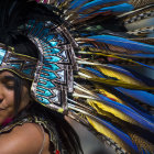 Colorful close-up: Smiling woman in feathered headdress meets man in blue and gold.