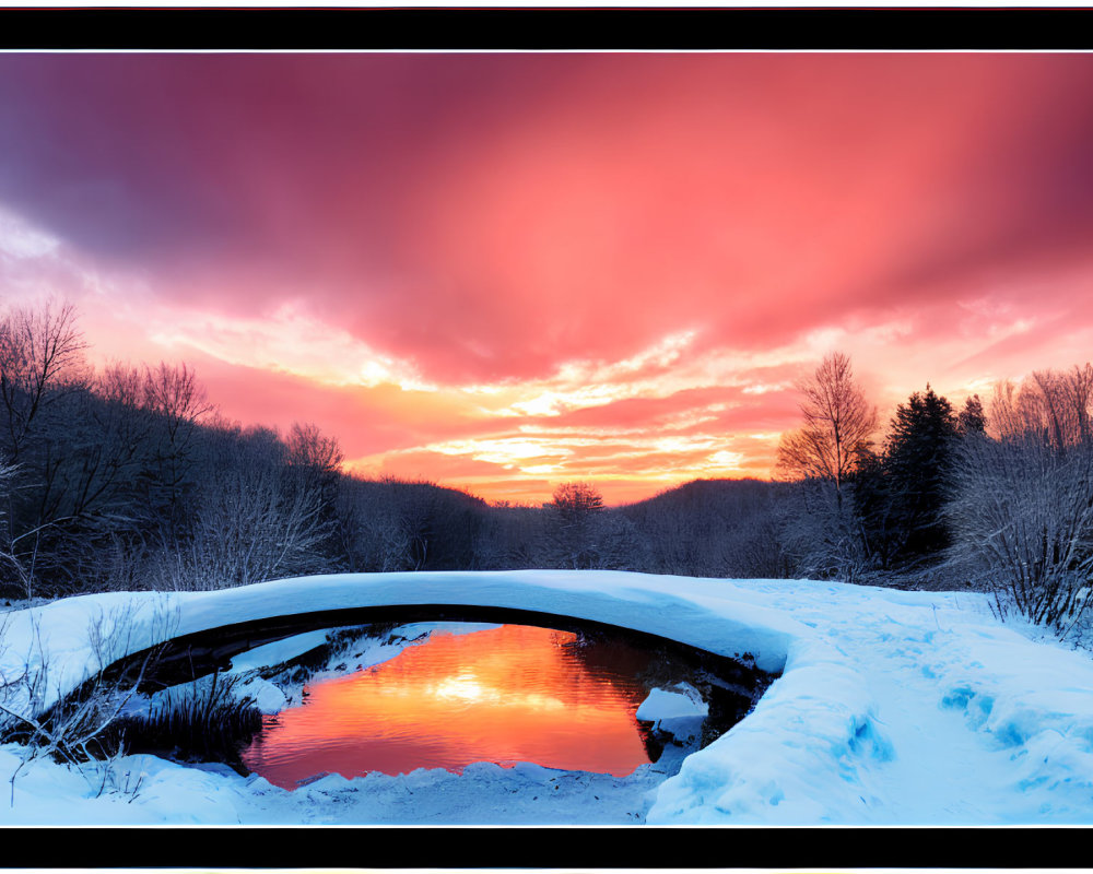 Fiery sunset reflecting on snow-covered river and bridge
