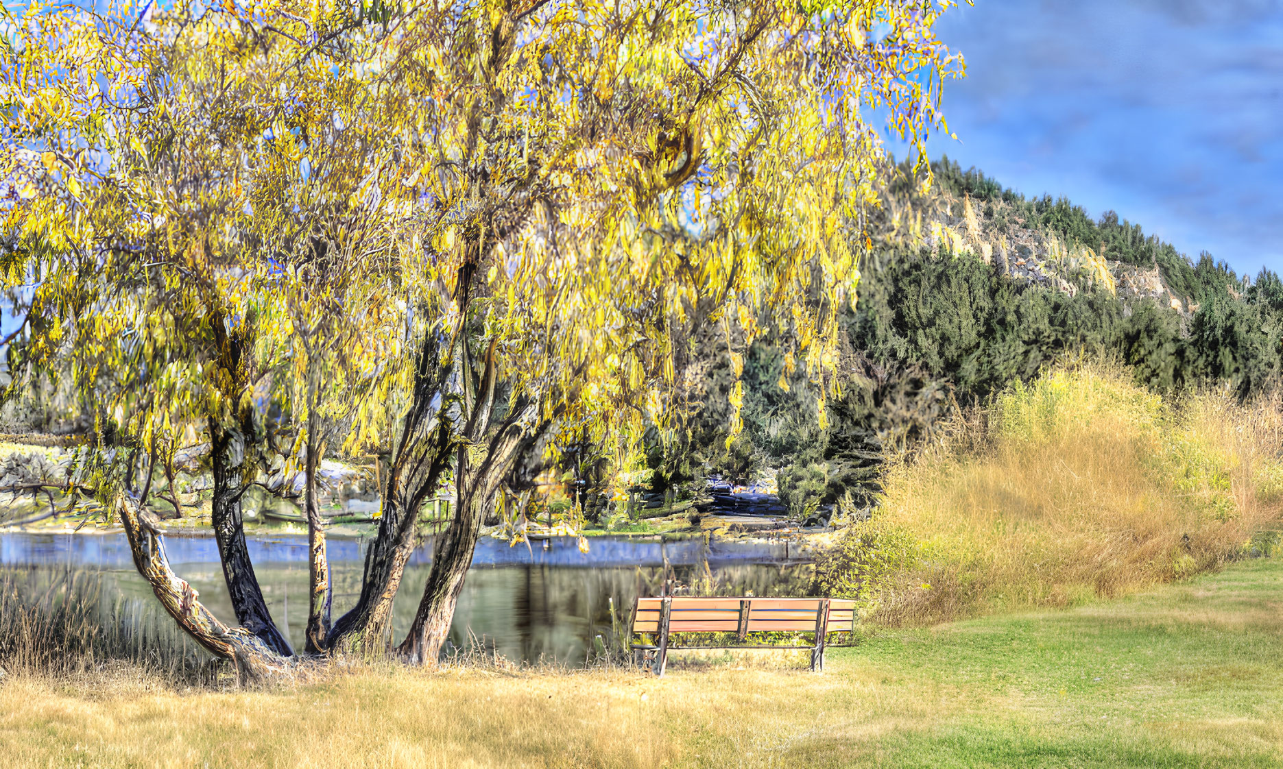 Tranquil Park Scene: Bench, Yellow Leaves, River, Vegetation, Hill