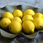 Vibrant yellow lemons on green ceramic dish on beige surface