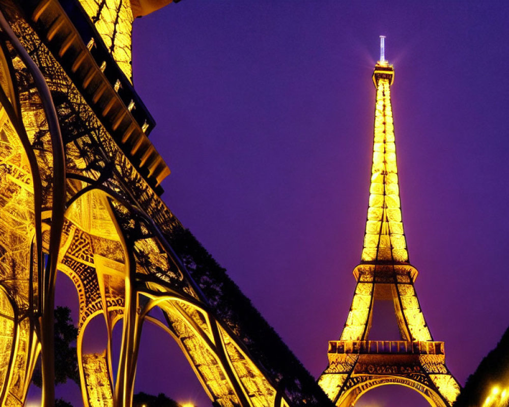 Eiffel Tower illuminated at night with golden lights against dusk sky