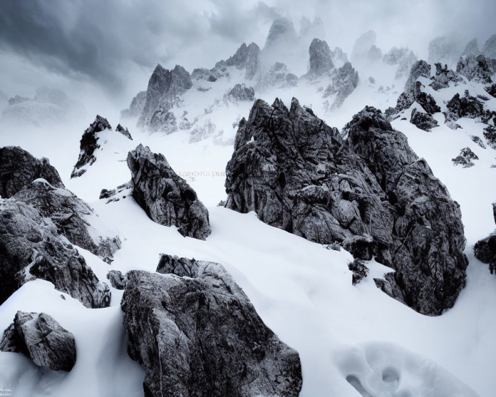 Monochrome mountain landscape with rugged rocks in snow under dramatic sky
