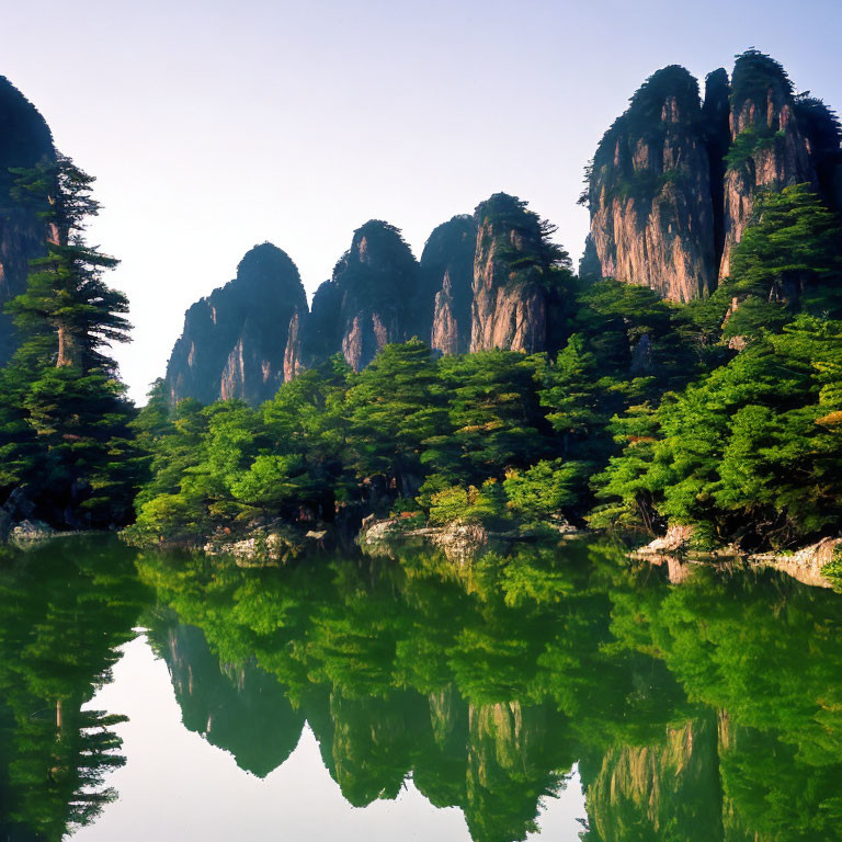 Jagged mountains reflected in serene lake amidst lush greenery