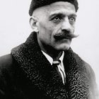 Monochromatic image of man with pointed ears, dark hair, mustache, red teardrop