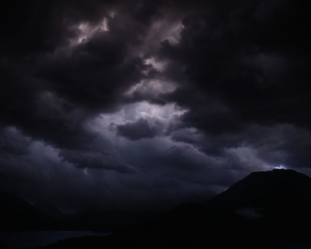 Dramatic night scene: mountains, dark clouds, subtle lightning