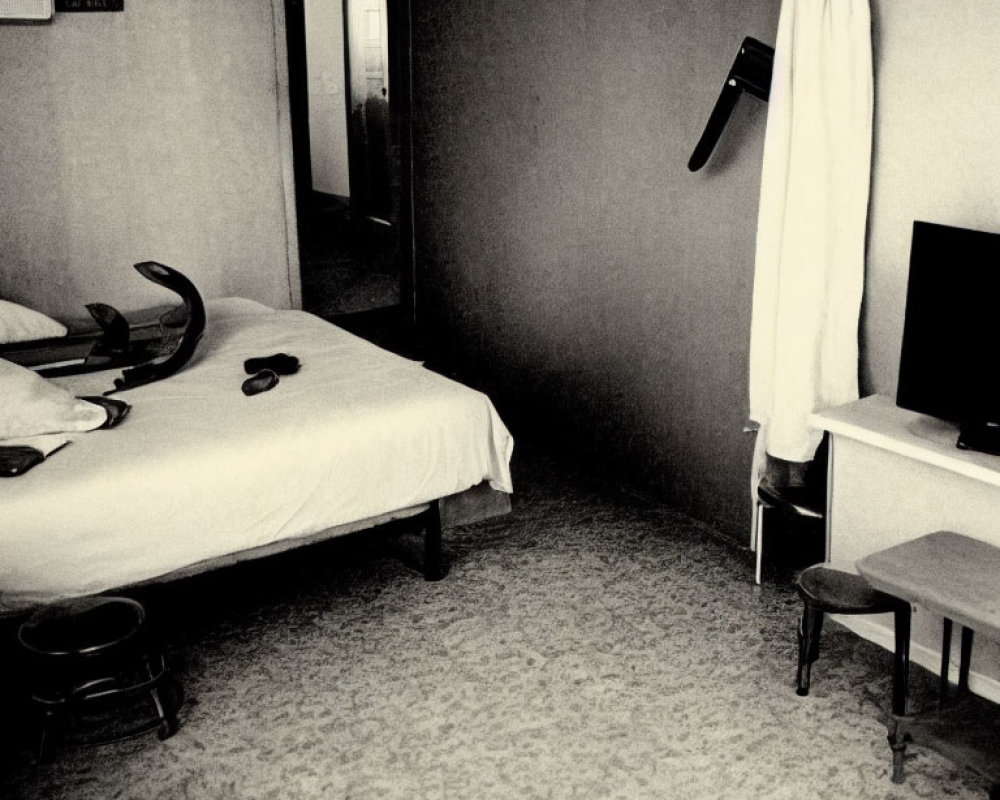 Monochrome hotel room with two beds, TV, chair, phone, and open door