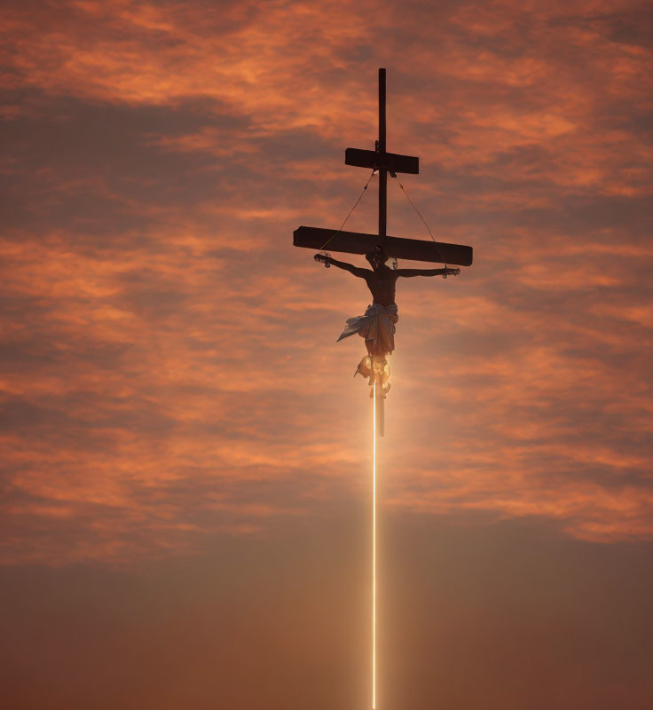 Silhouette of crucifix at sunset with orange clouds and sun rays