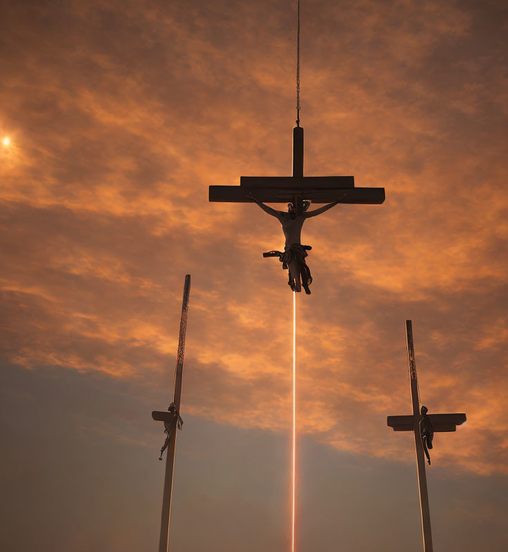 Silhouetted crosses against orange sky with Jesus figure and beam of light