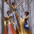 Elegant figurines in gold and blue gowns against woodland backdrop