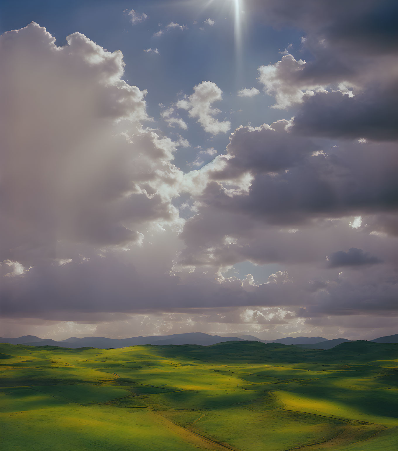 Dramatic sky over rolling green hills with sunbeams