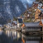 Medieval-style village by calm river with colorful houses, stone bridges, boats, dense forest, and