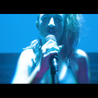 Passionate woman singing on stage with blue lighting