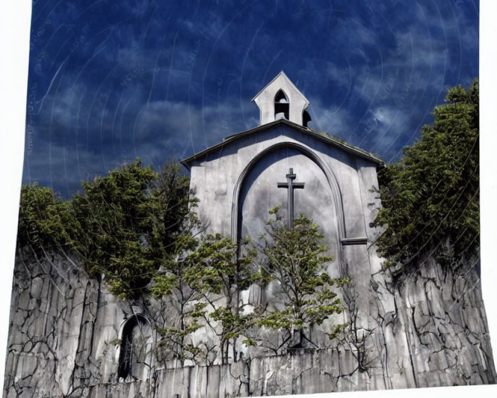 White facade church with cross, stone wall, greenery, blue sky.