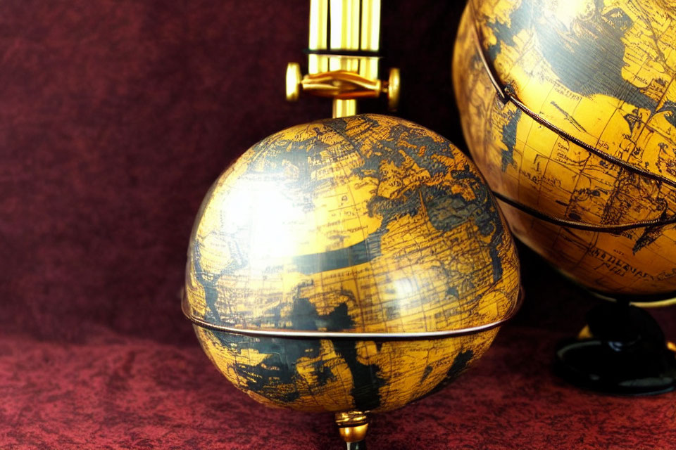 Vintage-style globes with golden finish on deep red background and intricate cartographic details.