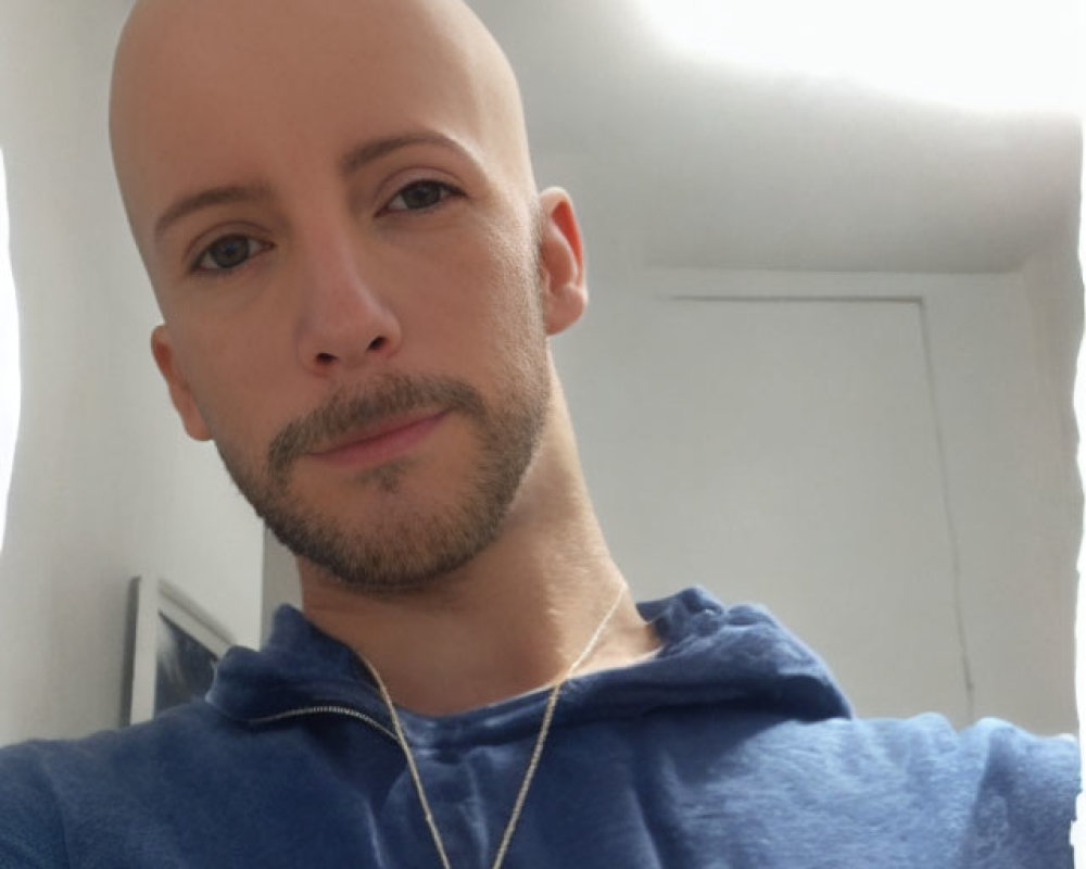 Bald Person in Blue Hoodie Smiling for Selfie