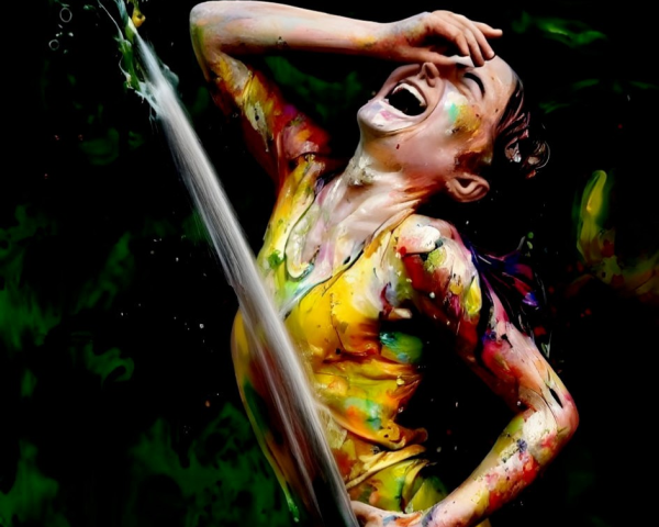 Colorfully painted person laughing in water splash scene