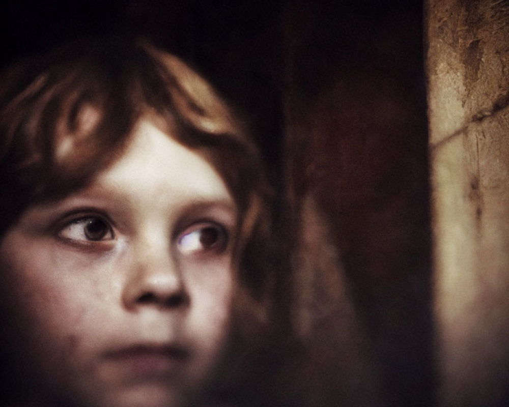 Child with Wavy Hair Contemplating in Dark Background