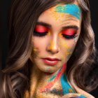 Colorful face paint portrait with twig crown and expressive eyes