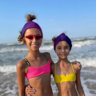Stylized female figures with futuristic goggles and colorful hair on a beach.